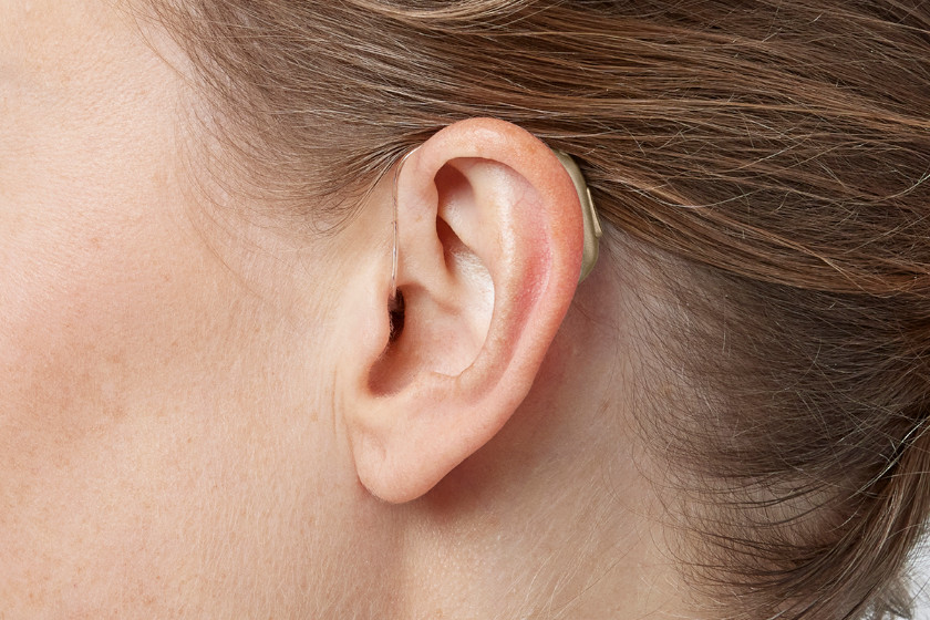 Mulher usando aparelho auditivo Philips HearLink em um ambiente moderno